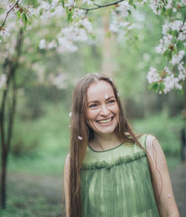 Smiling woman stretching gently outdoors in a green park.